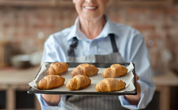 Bătrâna doamnă arată tavă cu croissante proaspăt coapte — Fotografie, imagine de stoc