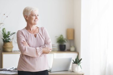 Pencereden bakan tatmin olmuş yaşlı iş kadını