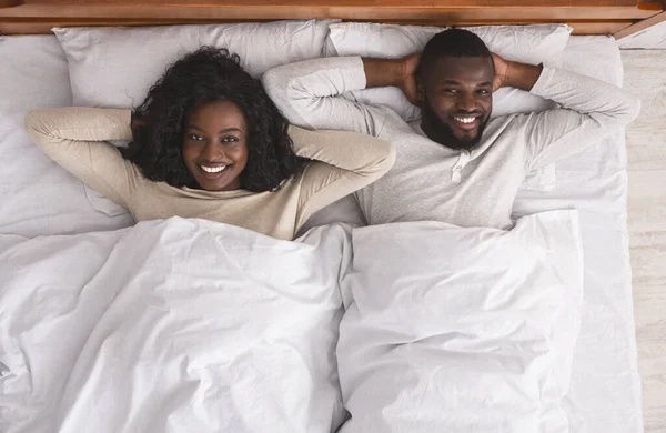 Задоволена пара відпочиває в ліжку з руками за головою — стокове фото