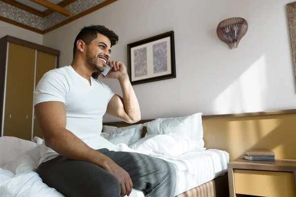 Chico alegre hablando por teléfono en la cama —  Fotos de Stock