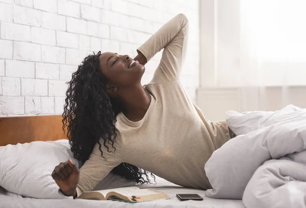 Νεαρή μαύρη γυναίκα που τεντώνεται στο κρεβάτι το πρωί. — Φωτογραφία Αρχείου