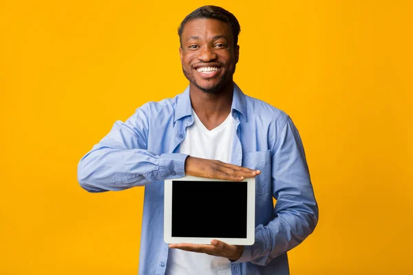 Positieve Afro Man toont blanco tablet scherm, gele achtergrond, Mockup — Stockfoto