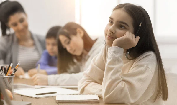 Glückliches Mädchen beim Tagträumen, beim Unterricht im Klassenzimmer sitzend — Stockfoto