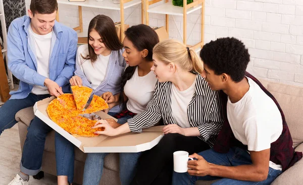 Des amis heureux prenant des tranches de pizza chaude de la boîte en carton — Photo