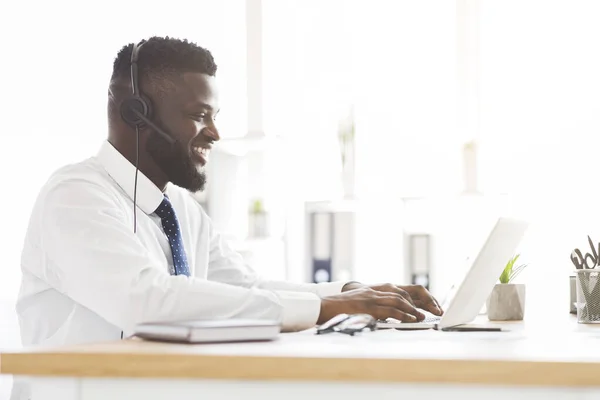 Zijaanzicht van de jonge medewerker van de klantenservice die in kantoor werkt — Stockfoto