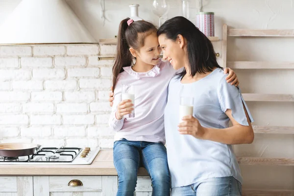 Mutter und Tochter trinken Milch in Küche und berühren Stirn — Stockfoto
