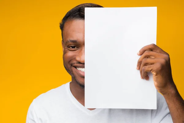 Hombre cubriendo la mitad de la cara con hoja de papel en el estudio —  Fotos de Stock