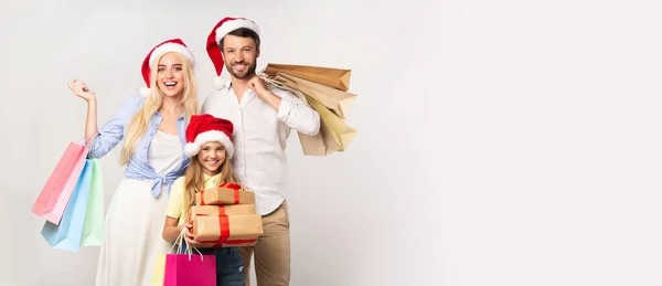Rodina v Santa klobouky nošení vánoční dárky na bílém pozadí — Stock fotografie