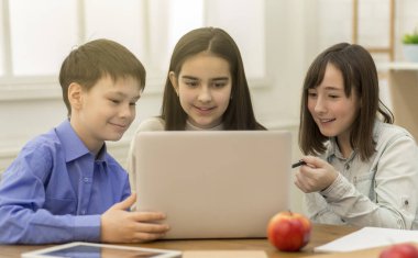Okulda dizüstü bilgisayar kullanan mutlu öğrenciler, video izliyorlar.