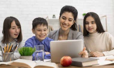Tablette çocuk dersleri gösteren genç öğretmen