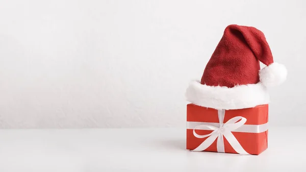 Regalo de Navidad rojo en el sombrero de Santas sobre fondo blanco — Foto de Stock