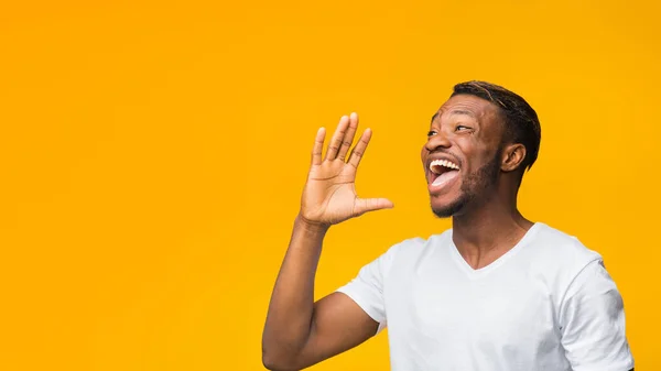 Zwarte man schreeuwen hand in de buurt van mond staande in de studio — Stockfoto