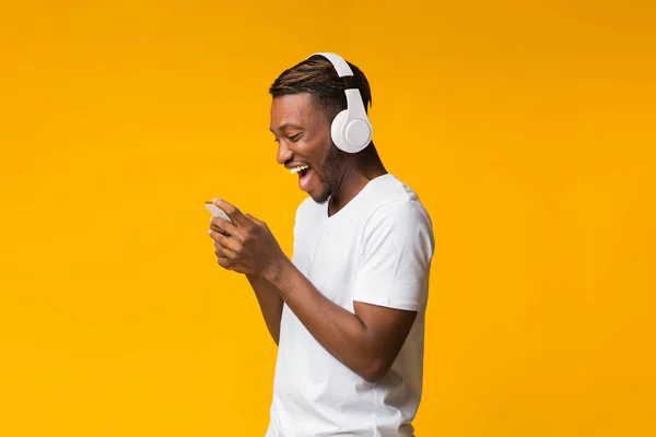 Schwarzer Mann mit drahtlosen Kopfhörern mit Smartphone im Studio — Stockfoto