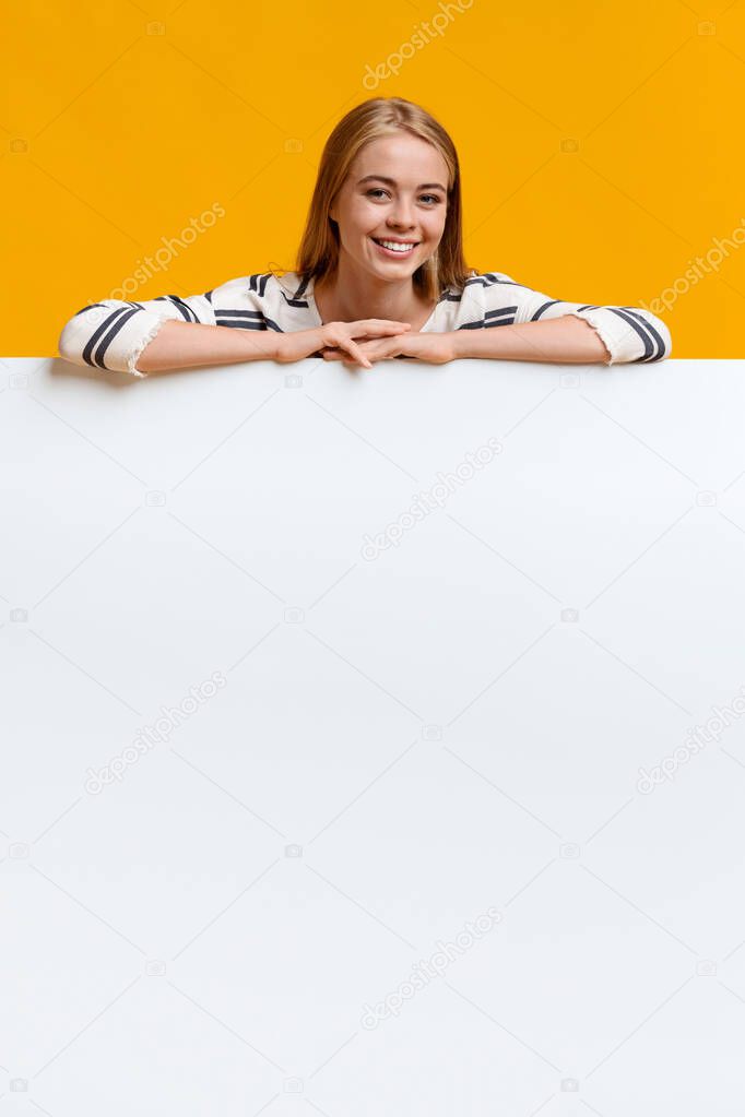 Beautiful teen girl leaning on blank white board
