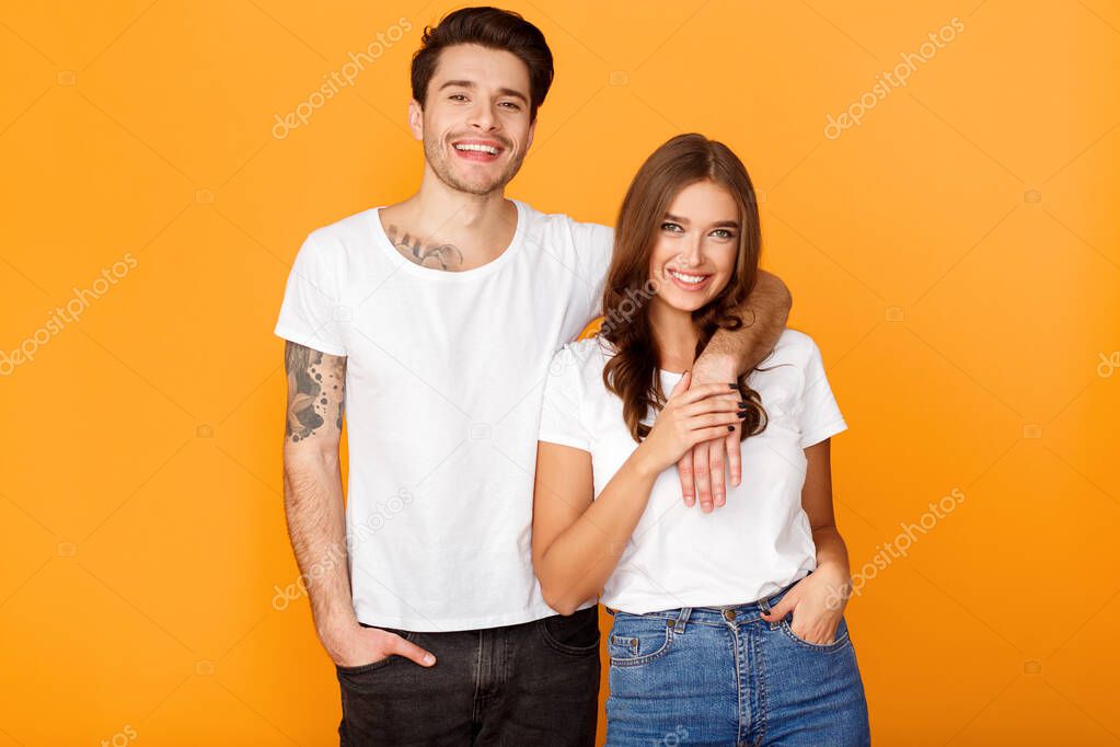 Fashionable couple posing over yellow studio background