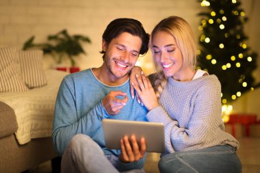 Mutlu çift tablet üzerinde sörf yapıyor Noel atmosferinin tadını çıkarıyor