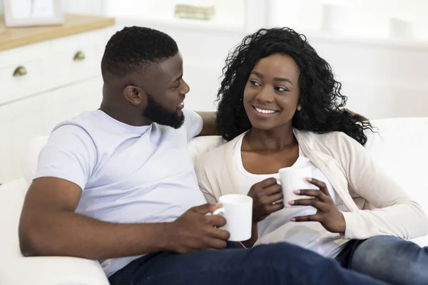 Afrikaans Amerikaans paar drinken koffie, ontspannen thuis samen. — Stockfoto