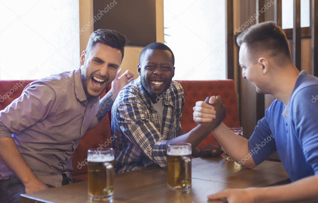 Arm Wrestling. Male Friends Having Fun In Bar