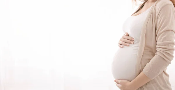 Femme enceinte embrassant son ventre, fond panoramique blanc — Photo