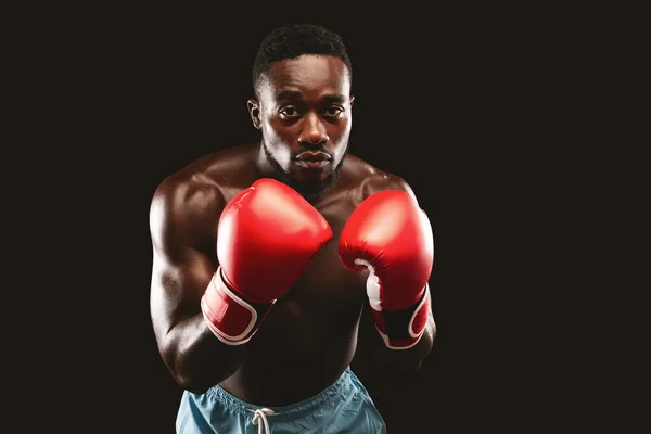 Joven boxeador muscular en la postura de ataque sobre fondo negro — Foto de Stock