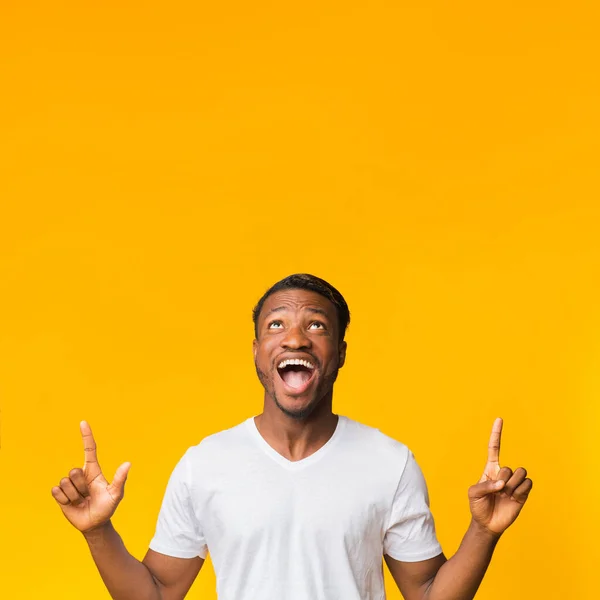 Opgewonden zwarte man wijzen vingers omhoog staande over gele achtergrond — Stockfoto