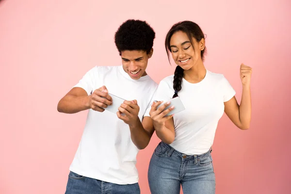 Glada tonåring par tävlar i videospel på smartphones — Stockfoto