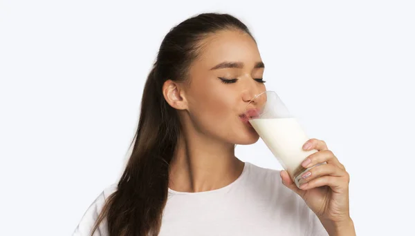 Jovem mulher bebendo leite de pé sobre branco estúdio fundo — Fotografia de Stock