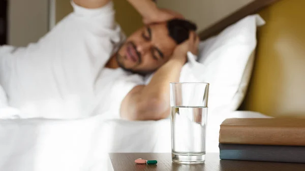 Young man suffering from migrane, lying in bed — Stock Photo, Image