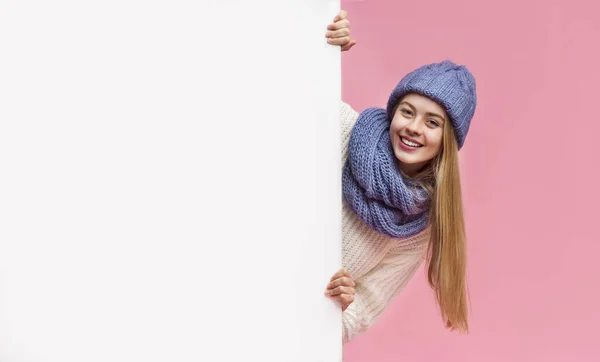 Blonde girl in winter hat staying next to blank board Stock Image