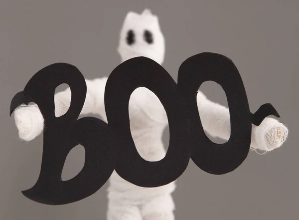 Biała postać ducha trzymającego boo litery w dłoniach na szarym — Zdjęcie stockowe