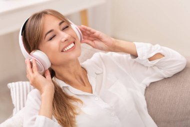 Kablosuz kulaklıklı mutlu kız evde müzik dinliyor.