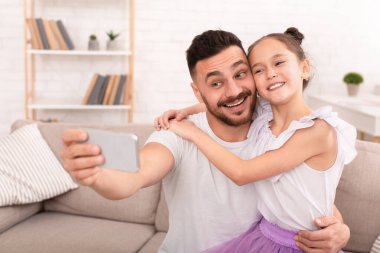 Mutlu baba ve çocuk cep telefonuyla selfie çekiyorlar.