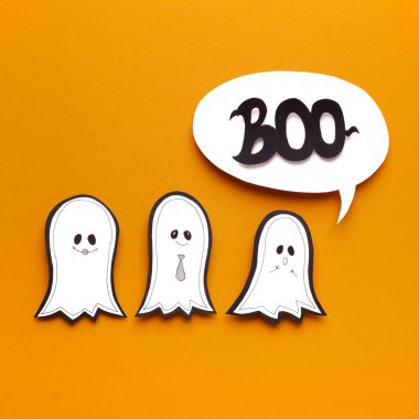 Üç şirin Cadılar Bayramı hayaleti turuncu üzerinde korkutucu olmaya çalışıyor.