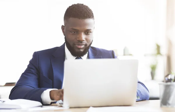 Jovem empresário concentrado trabalhando no escritório com laptop — Fotografia de Stock