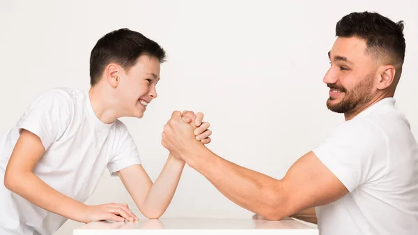 Papá e hijo juguetones compiten en la lucha libre de brazos —  Fotos de Stock
