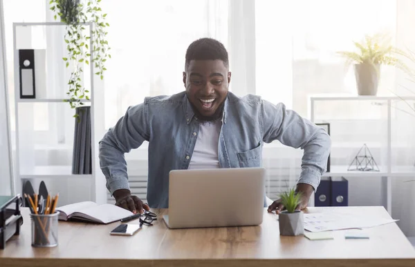 Alegre empleado negro mirando la pantalla del ordenador portátil con emoción — Foto de Stock