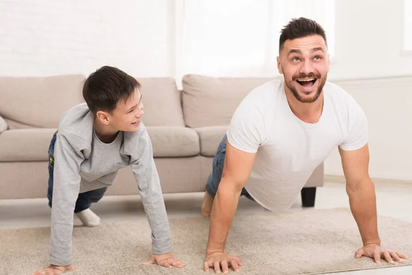 Pai ensinando seu filho fazendo exercícios push-ups — Fotografia de Stock