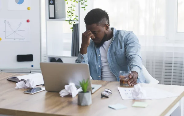 Trabalhador afro-americano stressado a beber álcool no local de trabalho — Fotografia de Stock