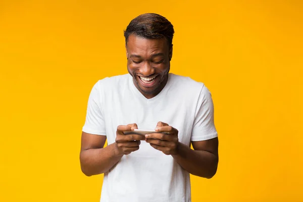 Homem negro excitado usando celular jogando jogos, Studio Shot — Fotografia de Stock