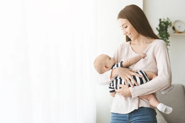 Hermosa madre milenaria sosteniendo a su lindo niño en las manos —  Fotos de Stock