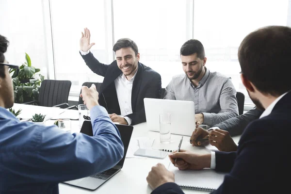 Zakenman steekt hand in hand en stelt vragen tijdens vergadering — Stockfoto