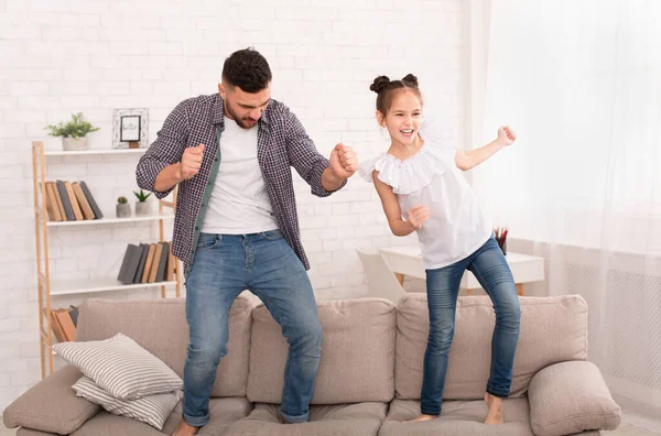 Linda filha e seu belo jovem pai pulando no sofá — Fotografia de Stock