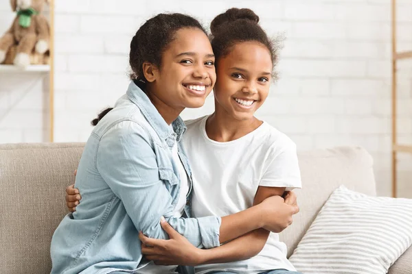 Dos encantadoras hermanas afroamericanas abrazándose en casa —  Fotos de Stock