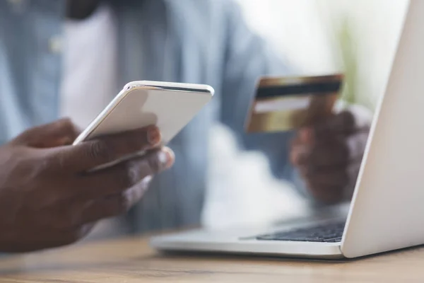 Hombre negro irreconocible usando teléfono inteligente y tarjeta de crédito, compras en línea — Foto de Stock