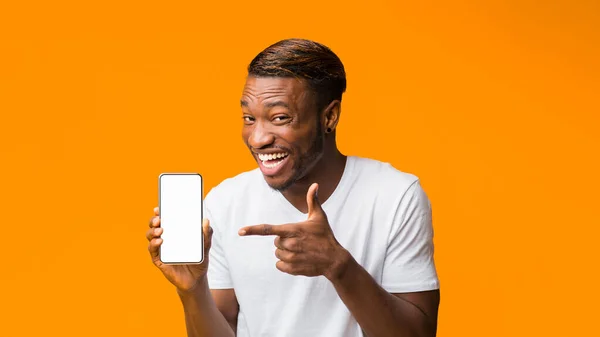 Hombre negro mostrando la pantalla en blanco del teléfono de pie, fondo naranja, burla —  Fotos de Stock