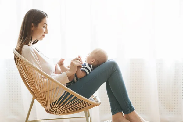 Matka z noworodkiem na kolanach siedzi na plecionym krześle — Zdjęcie stockowe
