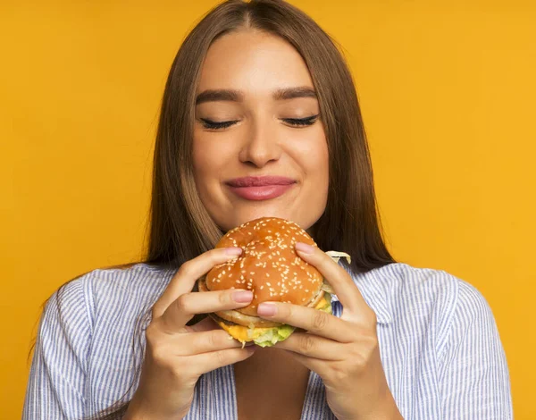 Ragazza felice mangiare hamburger in piedi, Studio Shot — Foto Stock