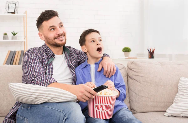 Papá e hijo disfrutando de la televisión con palomitas de maíz en casa — Foto de Stock