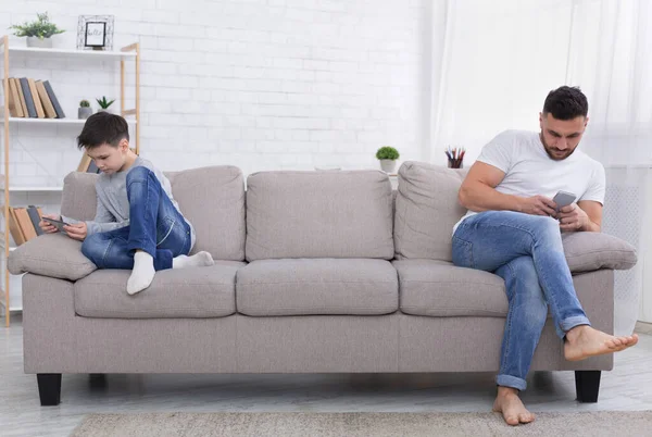 Adolescent garçon et son père emporté avec téléphones mobiles — Photo