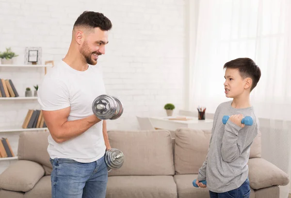 Feliz pai e filho se exercitando com halteres em casa — Fotografia de Stock